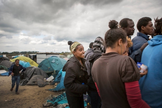 Een vrouw schuift aan bij de verdeling van hulpgoederen in Calais. (Foto Evy Menschaert)