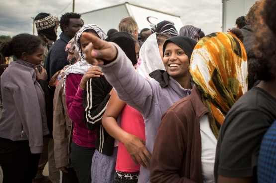 Vluchtelingen in Calais wachten in de rij voor hulpgoederen. (Foto Evy Menschaert)