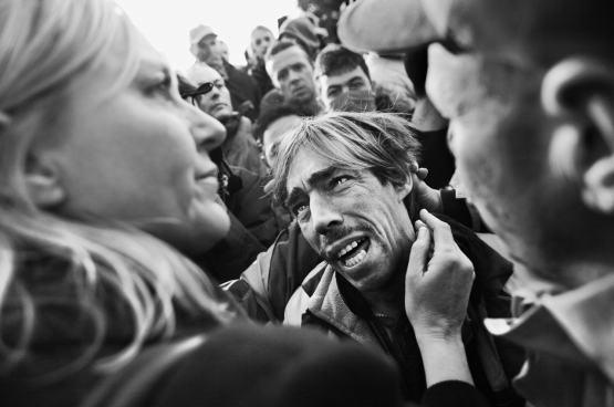 Stephan Vanfleteren. Ik was gepakt toen ik die VW-arbeider daar zo zag staan. Je moet weten: dat was geen beeld van een paar seconden, hij stond daar al een tijdje, en was stilaan door het lint aan het gaan. Ik wilde op een of andere manier iets zeggen tegen die man. Hem een schouderklopje geven, of zo. Niet dat zoiets het verschil maakt, maar ik had echt te doen met die kerel. Een wenende man die, bijna op z’n knieën, temidden zijn vrienden, uitschreeuwt: ‘ma famillie, ma maison, j’ai tout perdu…’ Ik krijg het er nog koud van. (Foto Stephan Vanfleteren)